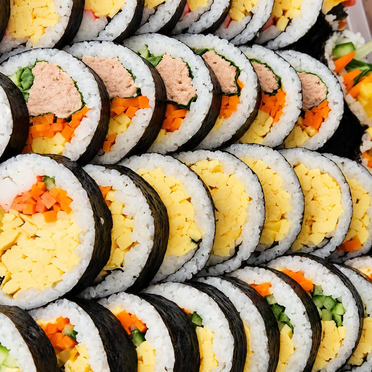 Nahaufnahme geschnittener Kimbap-Rollen mit Ei, Karotte, Gurke und Füllung